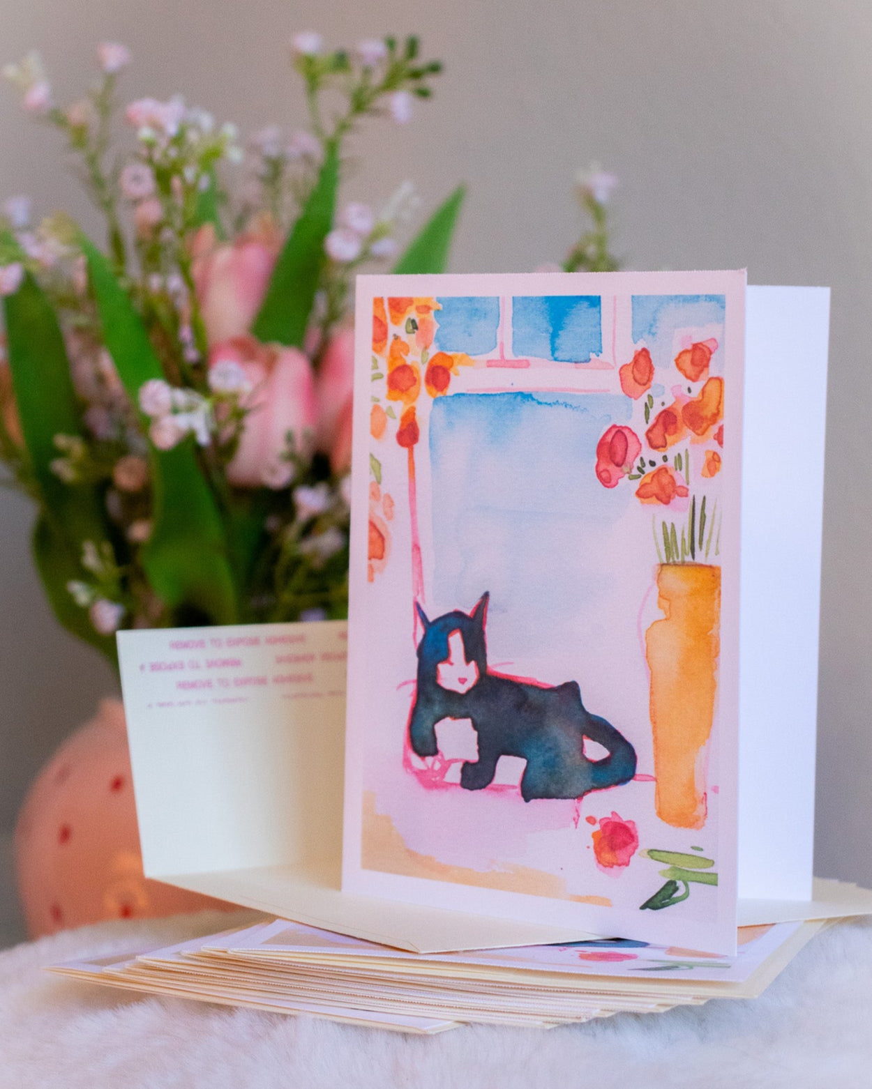 Set of greeting cards with a cat illustration on a soft surface with flowers in the background